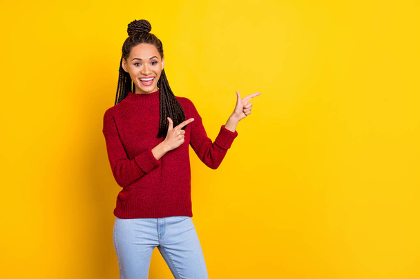 Photo of cute adorable dark skin woman dressed red sweater pointing empty space smiling isolated yellow color background - Fotó, kép
