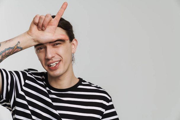 Young white man with earring smiling and pointing finger upward isolated over white background - Foto, immagini