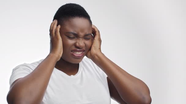 Genç şişman Afrikalı Amerikalı kadın migren krizi geçiriyor, acı dolu kafasına dokunuyor ve yüzünü buruşturuyor. - Video, Çekim