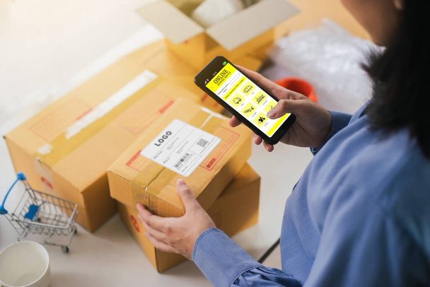 Business woman management parcel with technology smartphone application. Business owner using application Shipping Service for contact transportation company. Selective focus. - Foto, immagini