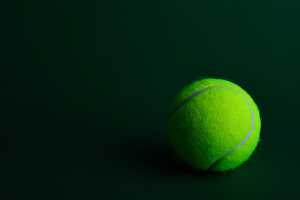 Single tennis ball on green background - Foto, afbeelding