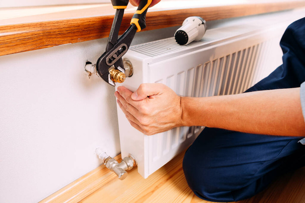 Repair heating radiator close-up. man repairing radiator with wrench. Removing air from the radiator - Фото, зображення