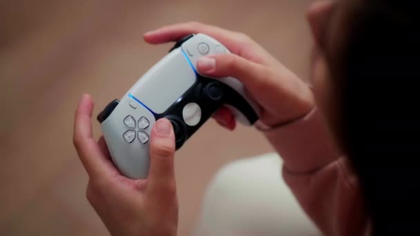 Het meisje drukt actief op de knoppen op de draadloze joystick tijdens het spelen van de consoles.Close-up, frame van bovenaf - Video