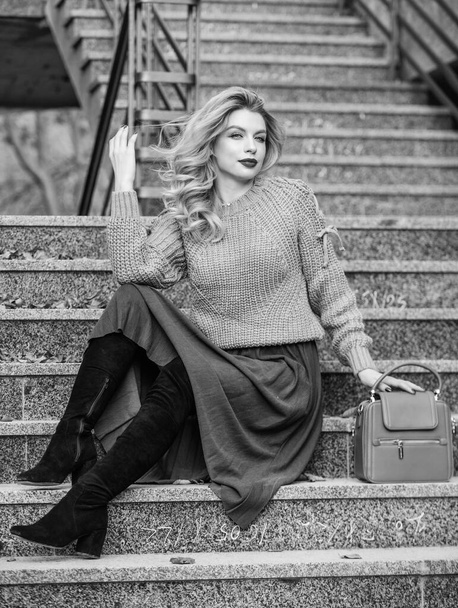 Fall outfit formula. Style Sweater and Skirt Combo for Fall. Woman gorgeous hairstyle sit on stairs outdoors. Warm autumn. Fall fashion trend. Wearable trends. Layer oversize knit over girly skirt - Foto, afbeelding