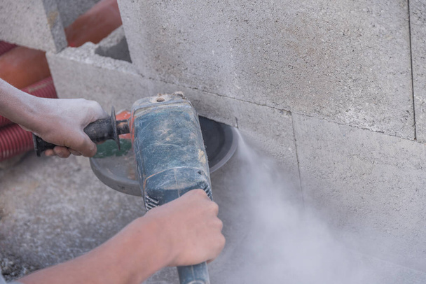 Blootstelling van een bouwvakker met een haakse slijper aan stof en lawaai - Foto, afbeelding