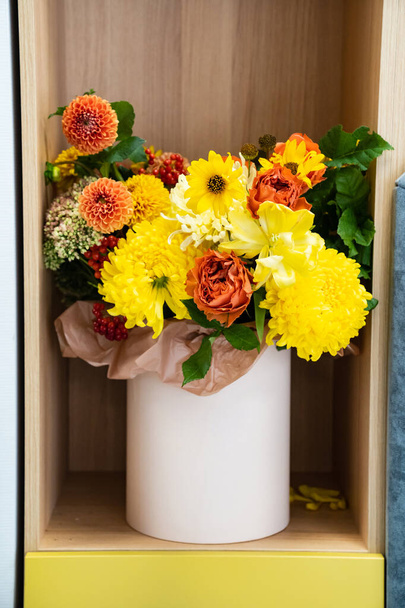 a bouquet of yellow and orange flowers in a hat box on a shelf in the closet.  - Fotó, kép