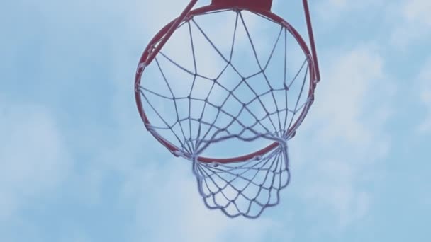 Cesta de baloncesto contra un cielo azul con nubes en las que la pelota golpea - Imágenes, Vídeo