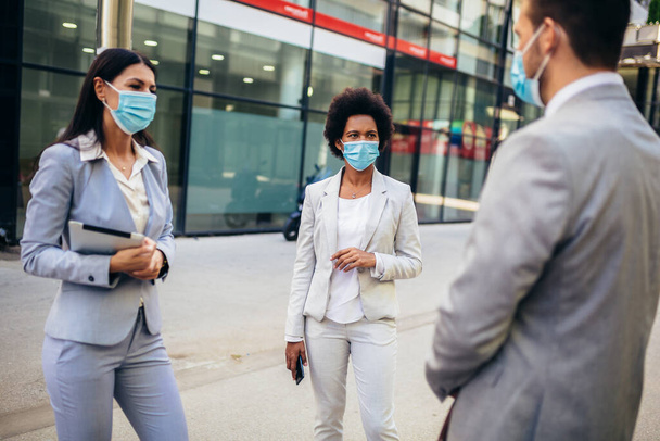 Three employers standing in social distance wearing face mask looking at each other and talking - Photo, image