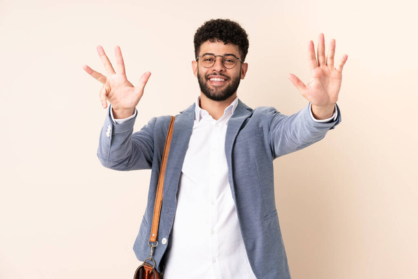 Junger Geschäftsmann marokkanischer Abstammung auf beigem Hintergrund, der mit den Fingern neun zählt - Foto, Bild