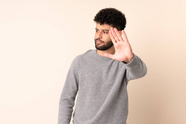 Young Moroccan man isolated on beige background making stop gesture and disappointed - Photo, Image