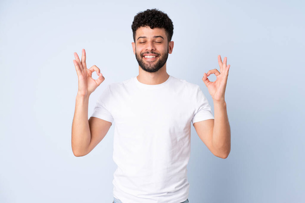 Young Moroccan man isolated on blue background in zen pose - Foto, afbeelding
