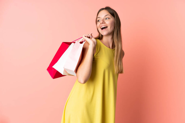 Mladý litevský žena izolovaný na růžové pozadí drží nákupní tašky a usmívá - Fotografie, Obrázek