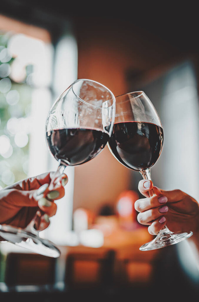 Young women hands holding glasses of red wine and clinking wine glasses in cafe or restaurant - Photo, Image