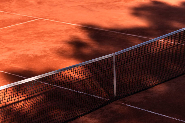 Oranssi tenniskenttä verkko varjoilla. Horisontaalinen urheilujuliste, onnittelukortit, otsikot, verkkosivusto - Valokuva, kuva