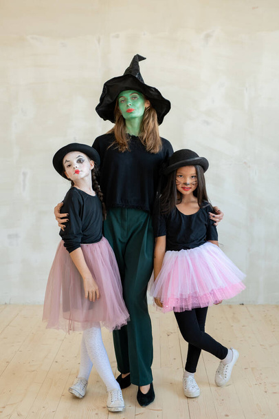 Giovane strega con il suo volto dipinto verde abbracciando due ragazze - Foto, immagini