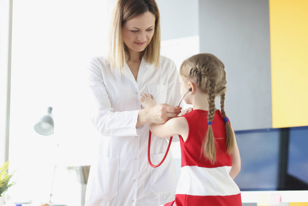 Лікар-педіатр кладе стетоскоп на маленьку дівчинку в клініку
 - Фото, зображення