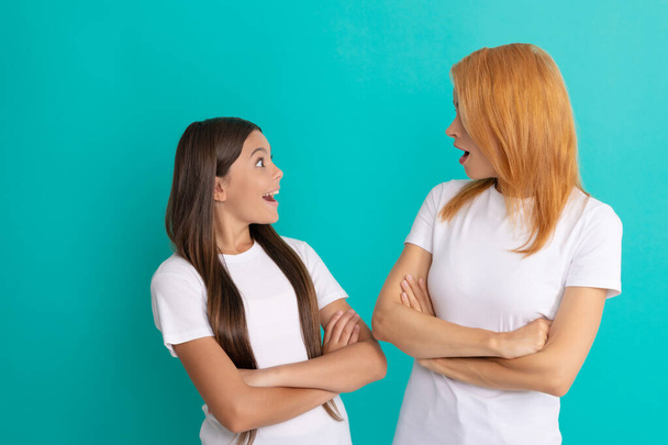 amazed mom and daughter with straight hair in white shirts crossed hands, amazement - Foto, Bild