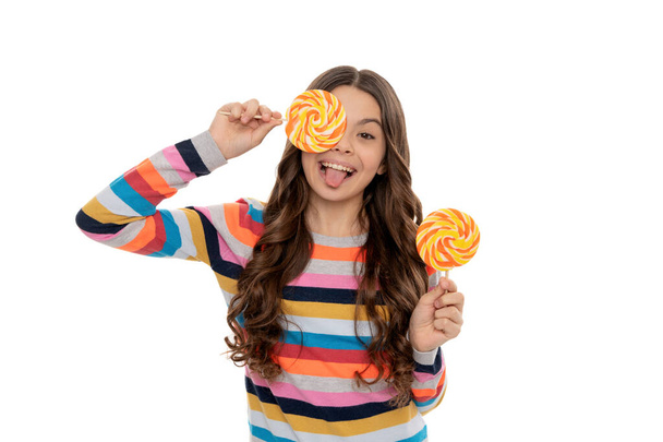 grappig tiener meisje in trui met lolly snoep op stok geïsoleerd op witte achtergrond, karamel winkel. - Foto, afbeelding