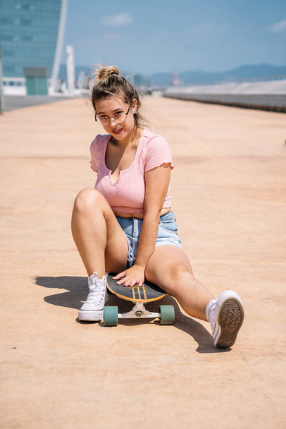 Portrait young blonde woman with skateboard wearing a glasses - Foto, Imagen