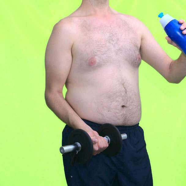 中年のふわふわの男ダンベルとボトルを持ち上げる。コンセプトフィットネスは健康的なライフスタイルを減らす - 写真・画像