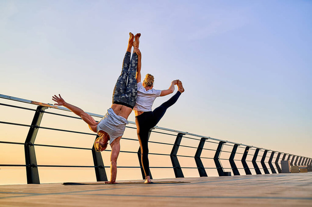 Couple practicing acrobatic handstand yoga together on nature outdoors at sea. - Фото, зображення