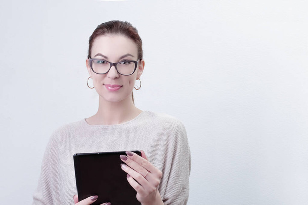 Portrait of woman holding modern tablet device feels happy. Woman in glasses using tablet pc on white background. Copy space - Foto, afbeelding