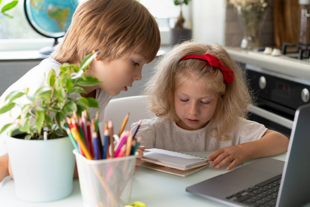 брат и сестра учатся дома на ноутбуке, детей и гаджетов. - Фото, изображение