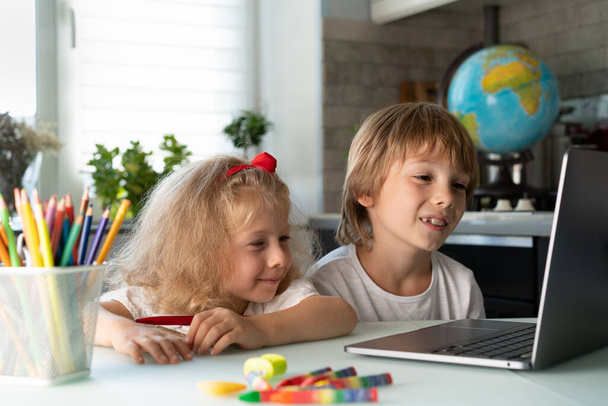 Geschwister lernen zu Hause mit Laptop, Kindern und Spielzeug. - Foto, Bild