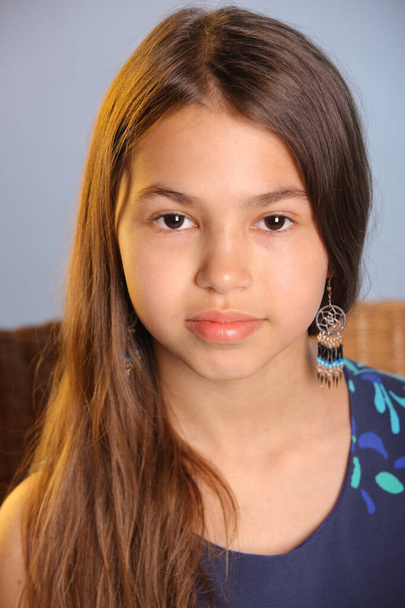 Close-up portrait of a beautiful dark-haired teenage girl 12 years old in a blue dress. She looks carefully eye to eye. - Foto, Bild