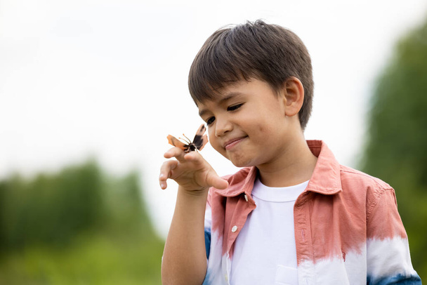 menino com borboleta na mão no fundo da natureza  - Foto, Imagem