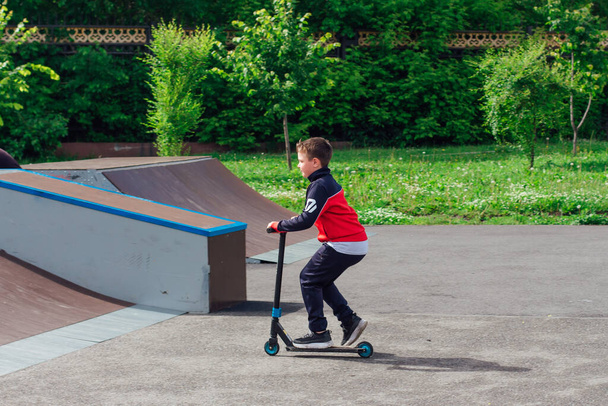 Novokuznetsk, Russia - July 19, 2021: Group of boys ride a scooter in an extreme park. Study of extreme sports on the open air. - 写真・画像