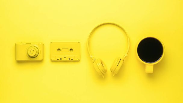 Κίτρινη κάμερα, ακουστικά, κασέτα και ένα φλιτζάνι καφέ σε κίτρινο φόντο. Τάση χρώματος. Κομψά αξεσουάρ. - Φωτογραφία, εικόνα