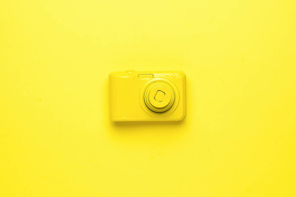 Eine knallgelbe Kamera auf leuchtend gelbem Hintergrund. Monochromes Bild der fotografischen Ausrüstung. Flache Lage. - Foto, Bild