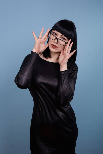 portrait of a beautiful girl with glasses posing for a photographer in the studio on a blue background - Fotografie, Obrázek