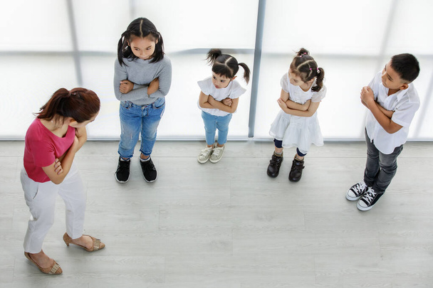 Draufsicht Aufnahme der asiatischen weiblichen Grundschule Leistung Lehrer unterrichten Gruppe von kleinen Jungen und Mädchen, um glücklich Spaß privaten Kindergarten Schauspielklasse durchführen. - Foto, Bild