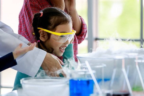 Азійські діти щасливі і допитливі спостерігають за реакцією на тестування лабораторією диму в науковому предметі на уроках з схвильованими і вдягнутими окулярами безпеки.. - Фото, зображення
