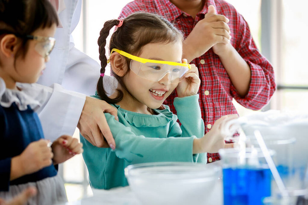 Asiatische Kinder beobachten freudig und neugierig die Reaktion von Rauchlabortests im naturwissenschaftlichen Fach im Unterricht mit aufgeregter Schutzbrille. - Foto, Bild