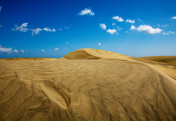 A scenic shot of sand dunes in a desert under the blue sky - Foto, afbeelding