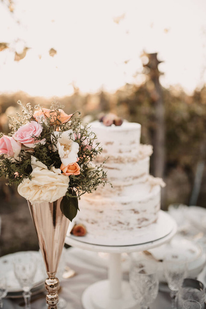 A vertical closeup of the wedding table with cake and a bunch of flowers. - Foto, immagini