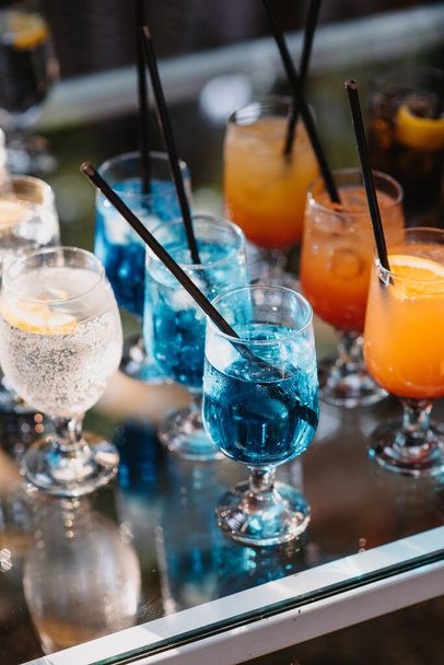 A vertical closeup of the colorful cocktails with black plastic straws. - Foto, afbeelding