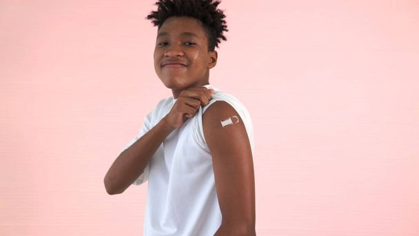 Afroamerikanischer Teenager zeigt fröhlich COVID-19 Impfverband - Foto, Bild