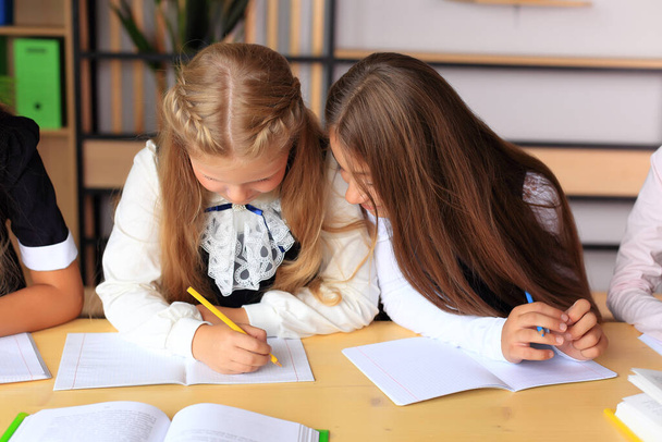 Eine junge Schülerin in Schuluniform schreibt in ein Notizbuch. - Foto, Bild