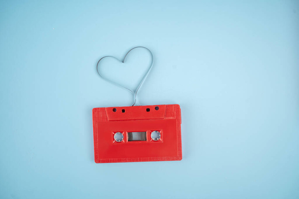 liefde voor muziek, gedraaide audioband in de vorm van een hart op een lichtblauwe achtergrond. - Foto, afbeelding