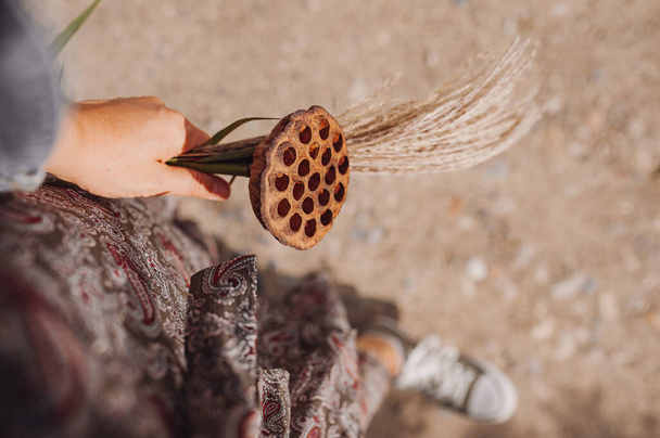 autumn bouquet in your hand. spikelets, dried flowers, dry lotus flower. atmospheric autumn picture. selective focus - Photo, Image
