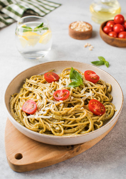 Spaghetti pasta with pesto sauce and cherry tomatoes on a plate. Menu, Italian cuisine. - Foto, Imagem
