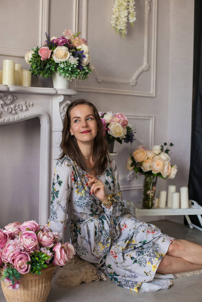 Mulher bonita sentada em um quarto entre as flores - Foto, Imagem