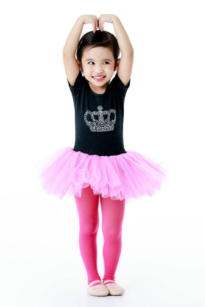 Portret geïsoleerde studio shot van kleine schattige kleuterschool ballerina danseres meisje in roze tutu ballet jurk legging en schoenen kostuum staande glimlachen poseren op witte achtergrond. - Foto, afbeelding