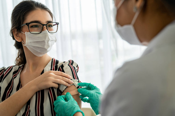 Une jeune femme consulte un médecin habile à l'hôpital pour se faire vacciner - Photo, image