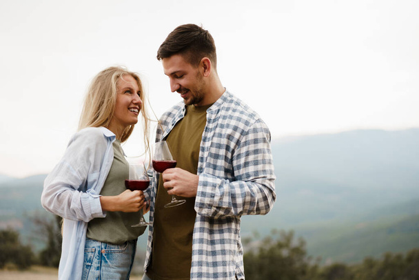 Smiling couple toasting wine glasses outdoors in mountains - Fotografie, Obrázek
