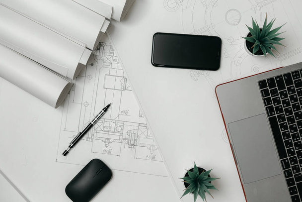 Laptop, telefone e rolos de desenhos na mesa em engenharia. fundo arquitetônico com rolos de desenhos técnicos - Foto, Imagem